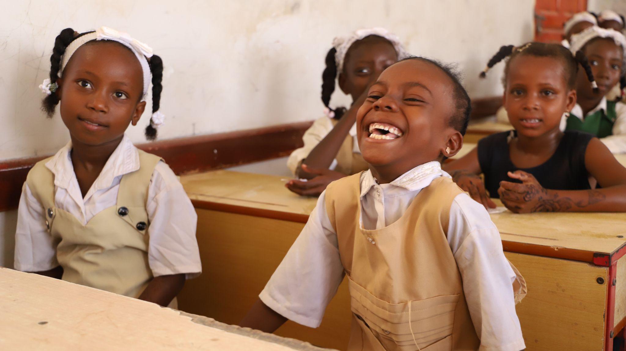 Schoolgirls laughing together at their desks in a classroom